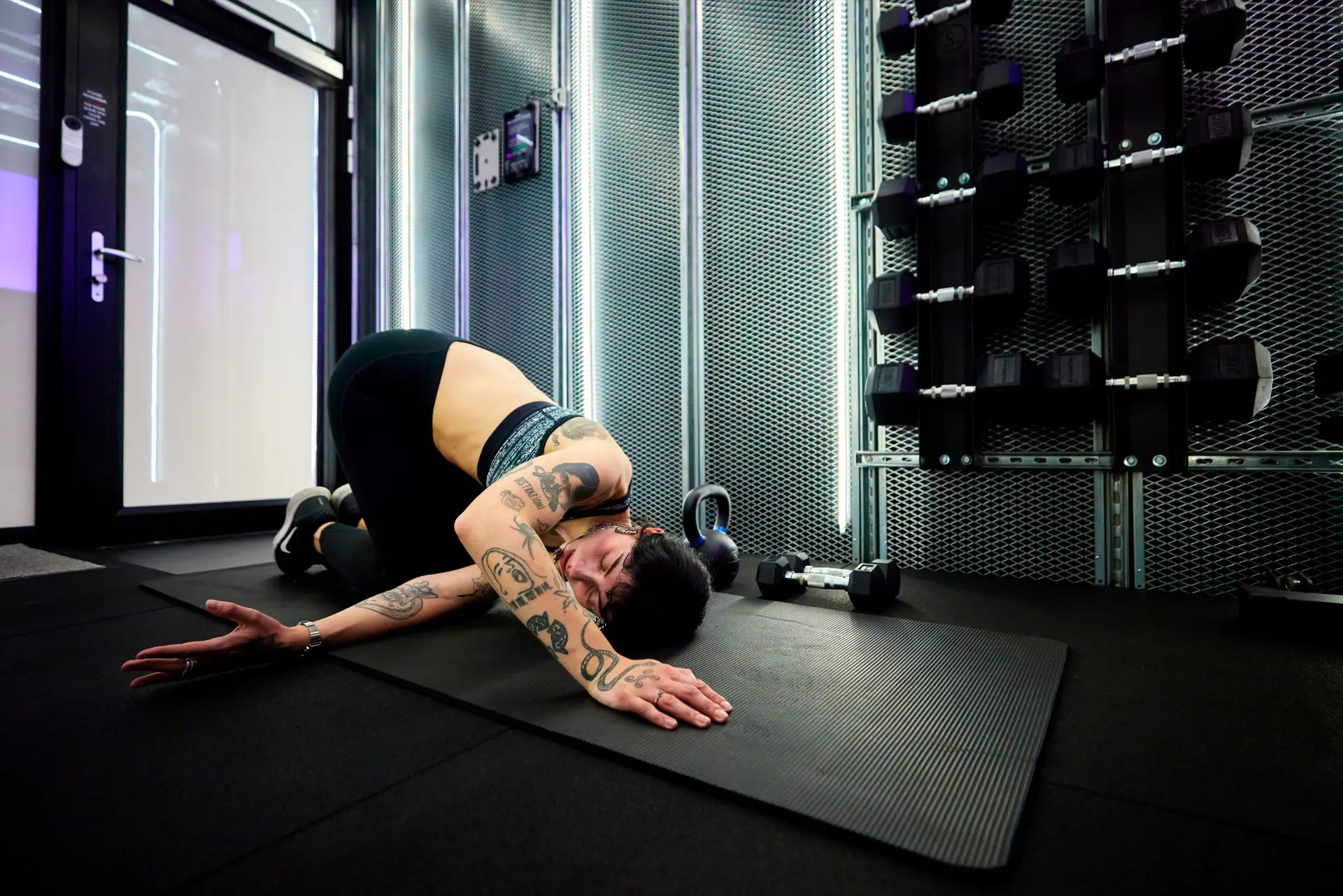 A woman stretching on a mat inside a PT Pod