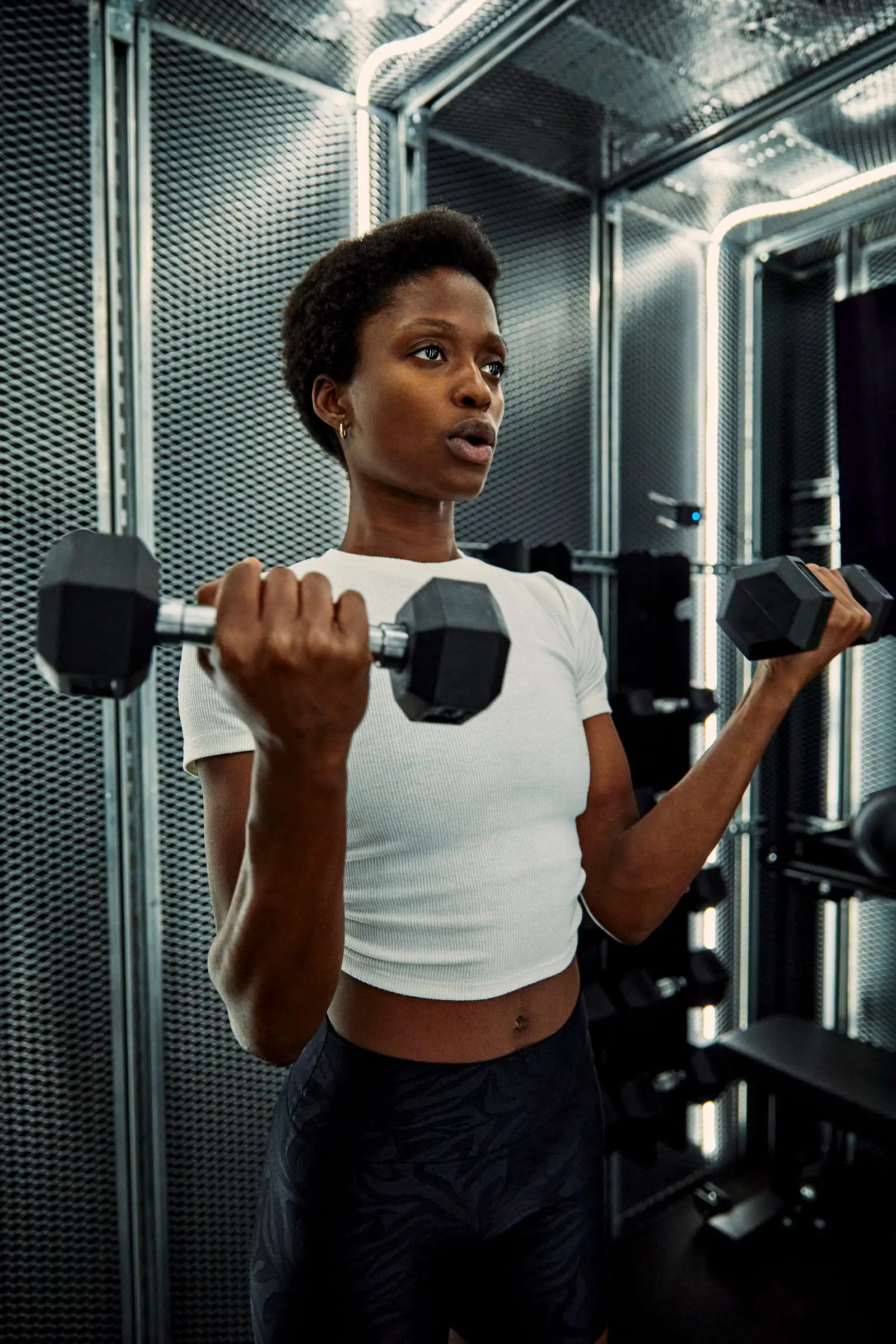 A woman doing dumbbell curls inside a PT Pod